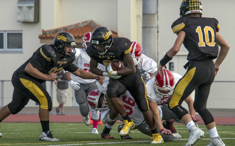 Kadena running back Abe Patterson tries to slither through the tackle of Nile C. Kinnick's Harry Cheng as teammates John Murphy and Cody Sego watch.