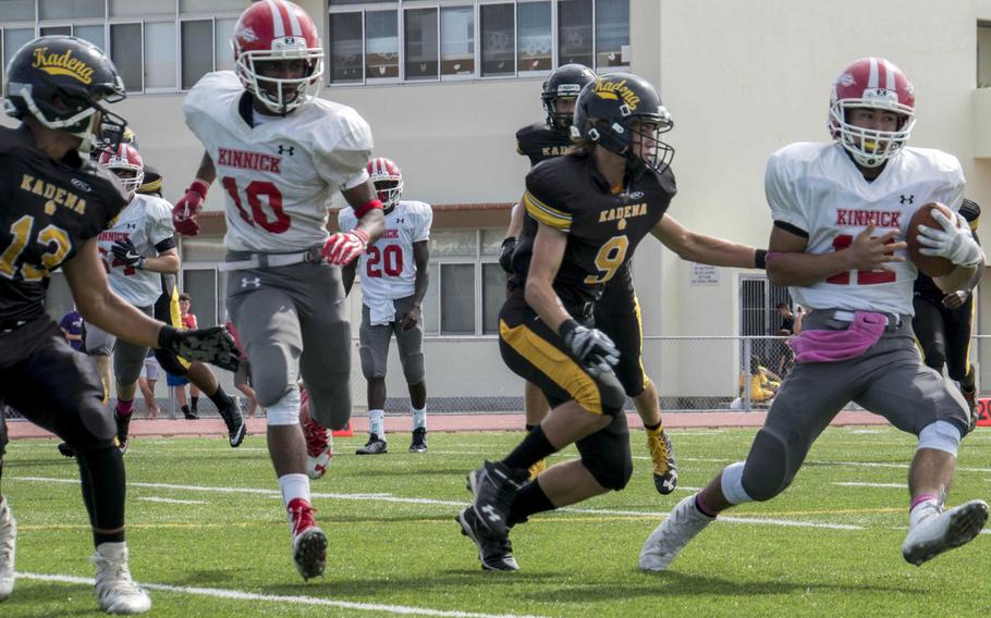 Nile C. Kinnick quarterback Kacey Walker gets run down by Kadena defender John Roush as Red Devils teammate Devoney Stanley tries to escort and Panthers defender Donte Savoy moves in.