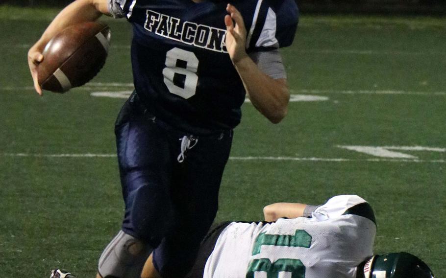 Seoul American quarterback David Messinger, a former Daegu player, runs for daylight past Warriors' Jacob Litton during Friday's game. Daegu won 18-8.