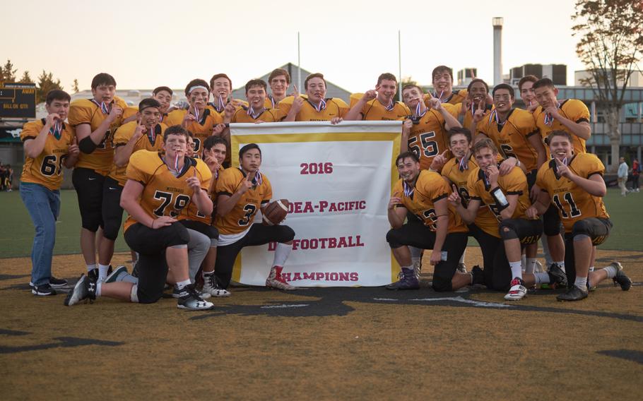 The ASIJ Mustangs pose with the championship banner following the Far East Division I Football Championship on Saturday at the American School in Japan in Chofu, Japan. ASIJ defeated Kadena 35-18 to claim its first Far East Football crown. 