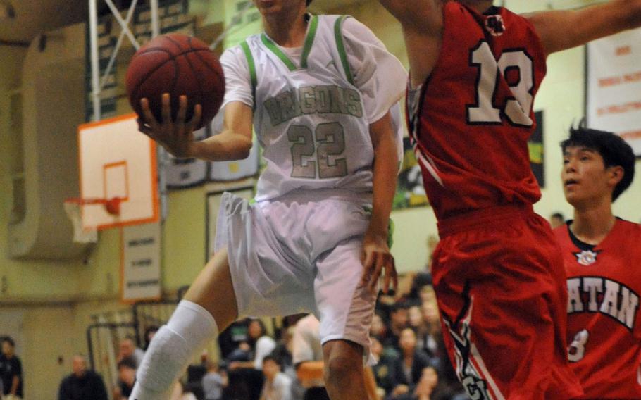 Kubasaki junior Elonzo Higginson III tries a scoop shot against two defenders Friday during the Dragons' 86-59 season-opening home win over Chatan.