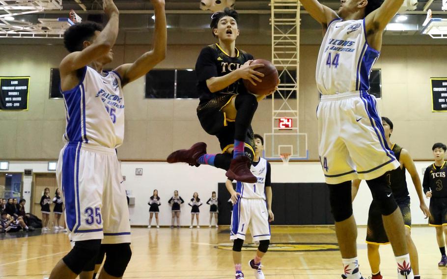 Taejon Christian guard Richard Redfern skies for a shot between Seoul American defenders DeAndre Metcalf and Quintin Metcalf during Friday's boys basketball game, won by the Falcons 73-35.