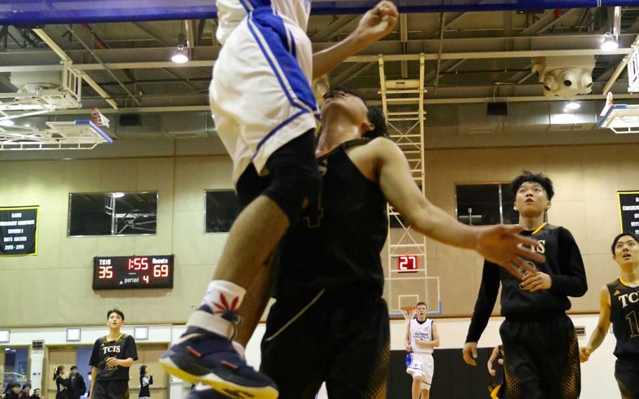 Seoul American sophomore Quintin Metcalf slam dunks the ball over Taejon Christian defender J.J. Jung during Friday's boys basketball game, won by the Falcons 73-35.