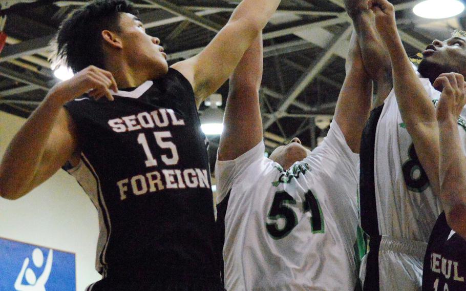 Daniel Bang of Seoul Foreign battles for a rebound against Elijah Benbischew and Jarvis Stokes of Daegu during Friday's boys basketball game, won by the Crusaders 55-50.