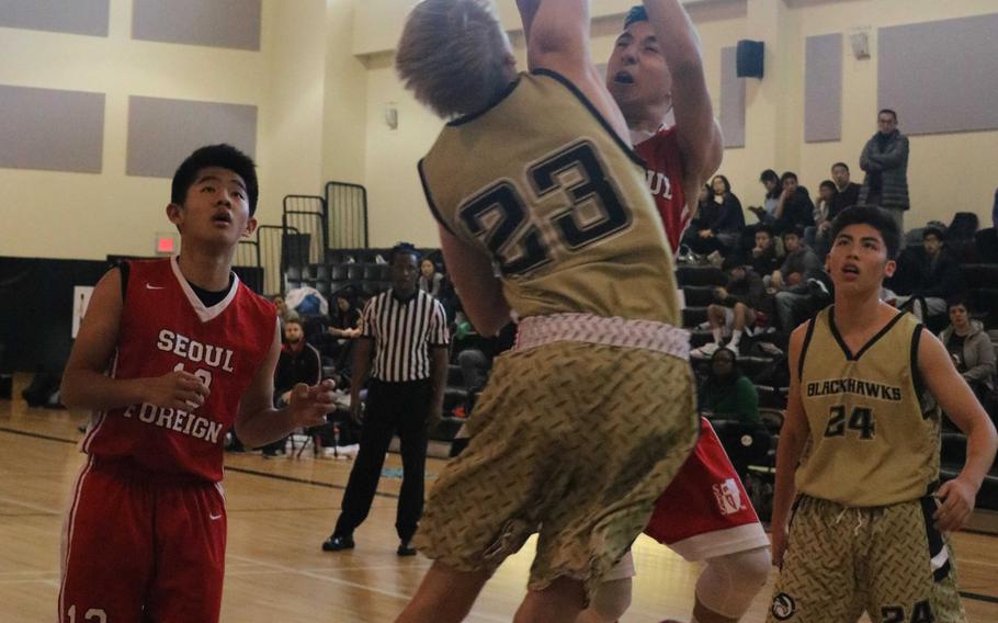 Seoul Foreign's Nicik Larsen has his path to the basket blocked by Humphreys' Jackson Taylor as the Crusaders' Brandon Sohn and the Blackhawks' Brice Bulotovich watch during Saturday's boys basketball game, won by the Blackhawks 54-51.
