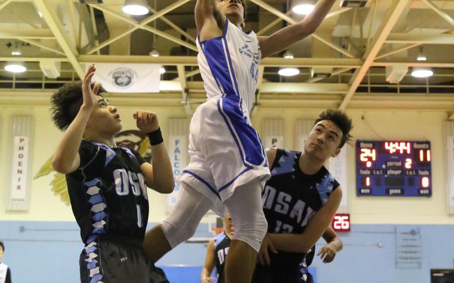 Seoul American's Quintin Metcalf slams one home between Osan defenders during Wednesday's boys basketball game won by the Falcons 60-37.