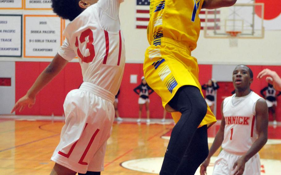 Yokota's Kory Sterling puts up a shot against Nile C. Kinnick's Kedrick Stockman and Jacob Germany during Tuesday's boys basketball game, won by the Panthers 61-50.
