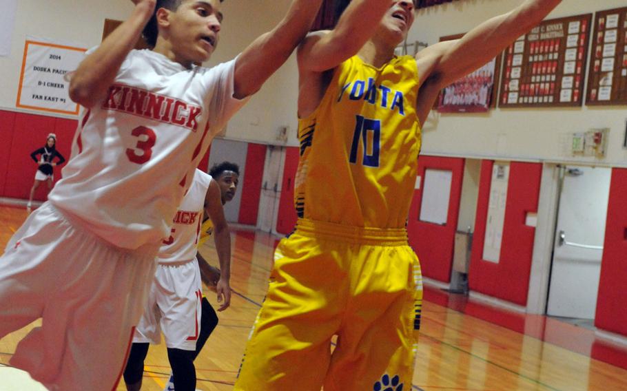 Yokota's Hunter Cort grabs a rebound against Nile C. Kinnick's Davion Roberts during Tuesday's boys basketball game, won by the Panthers 61-50. Yokota also beat St. Mary's 59-42 on Thursday.