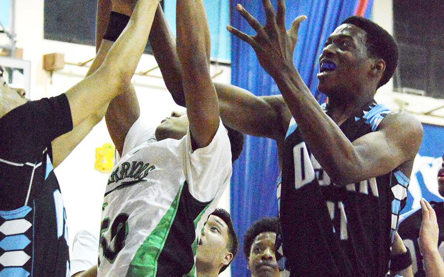 Jonathan Wilson of Daegu goes up for the ball between Osan American's Sung DeAngelo and Darius Dawson during Thursday's boys basketball game, won by the Warriors 54-40.