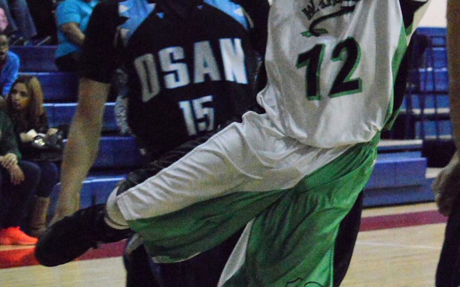 Kevin Williams of Daegu charges to the basket ahead of Osan's Sung DeAngelo during Thursday's boys basketball game, won by the Warriors 54-40.