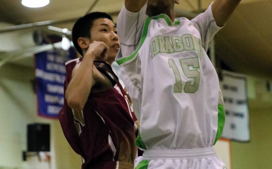 Kubasaki's Ilijah Washington skies for a rebound against a Naha Kokusai defender during Wednesday's boys basketball game, won by the Dragons 72-69 in overtime.