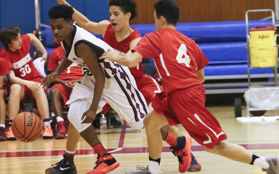 Zama's Rafael Labrador dribbles past Nile C. Kinnick's D'Angelo Burford and Davion Roberts during Tuesday's boys basketball game, won by the Red Devils 79-67.