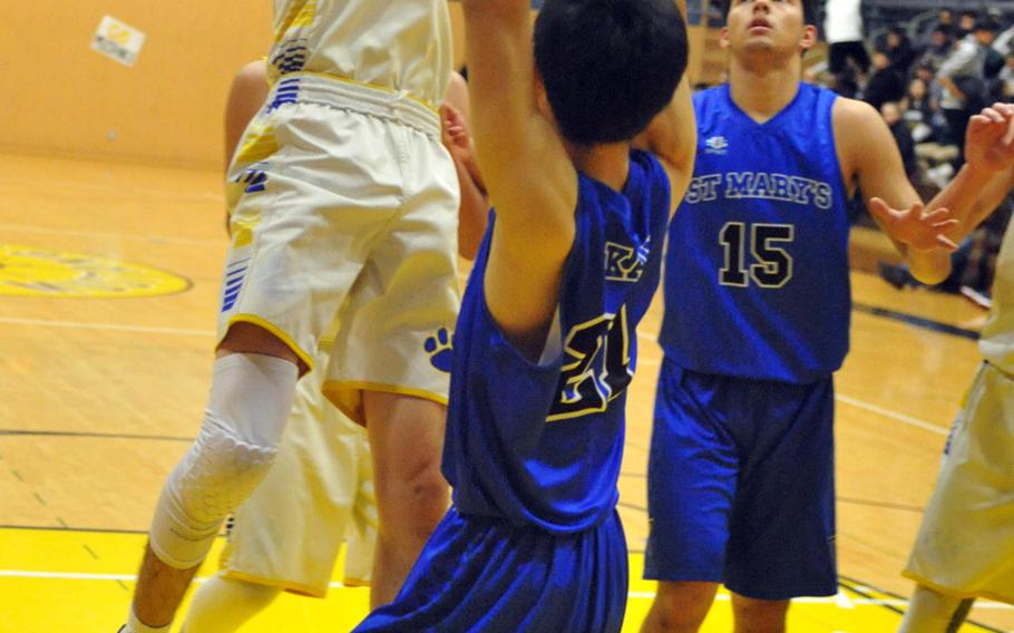 Yokota's Hunter Cort shoots over St. Mary's Jongdae Kang and Thomas Wood during Saturday's boys championship game in the ASIJ Kanto Classic basketball tournament. The Panthers downed the Titans 57-47.