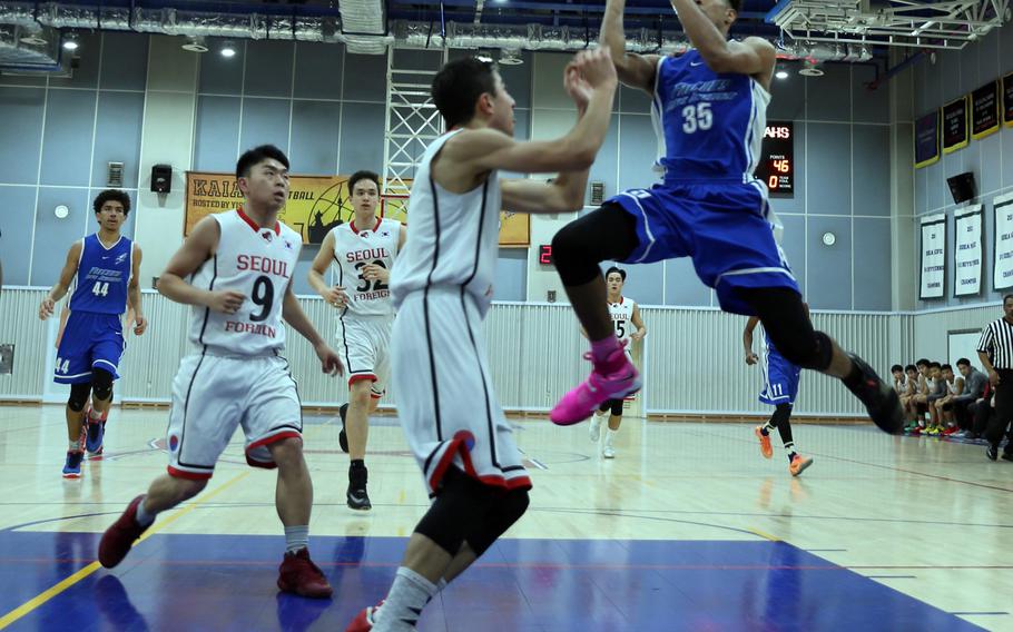 Seoul American's DeAndre Metcalf goes up for a shot over Seoul Foreign's defense during Friday's Korea Blue tournament semifinal. The Falcons won 83-50 and face Humphreys in Saturday's championship for the second straight year.