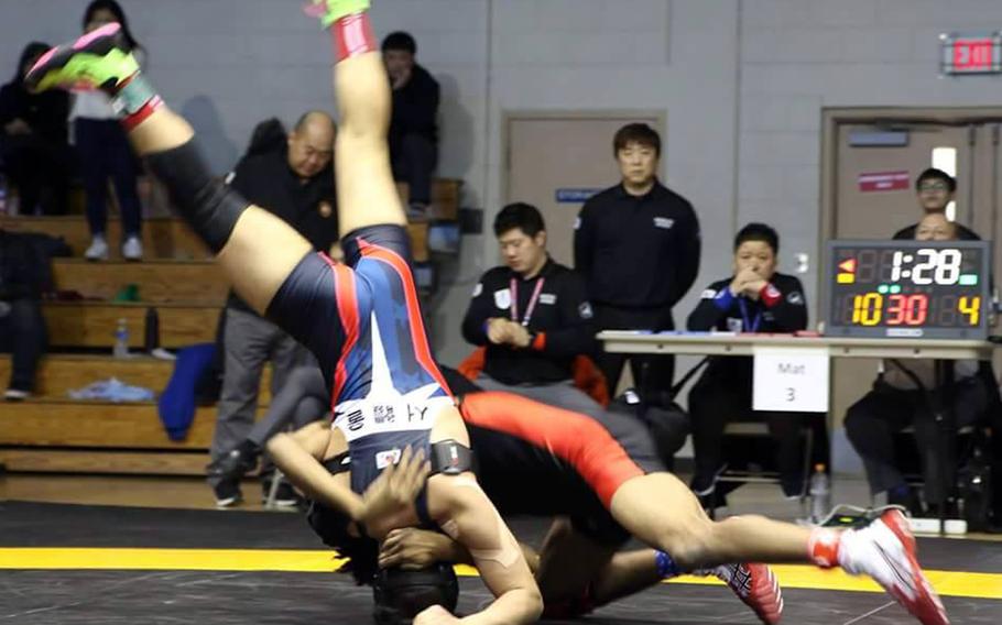 Nile C. Kinnick's Devoney Stanley wheels Seoul Ameircan's Eric Guzman onto his head during Friday's 129-pound championship in the Far East High School Wrestling Tournament. Stanley won by technical fall 14-4 in 2 minutes, 20 seconds.