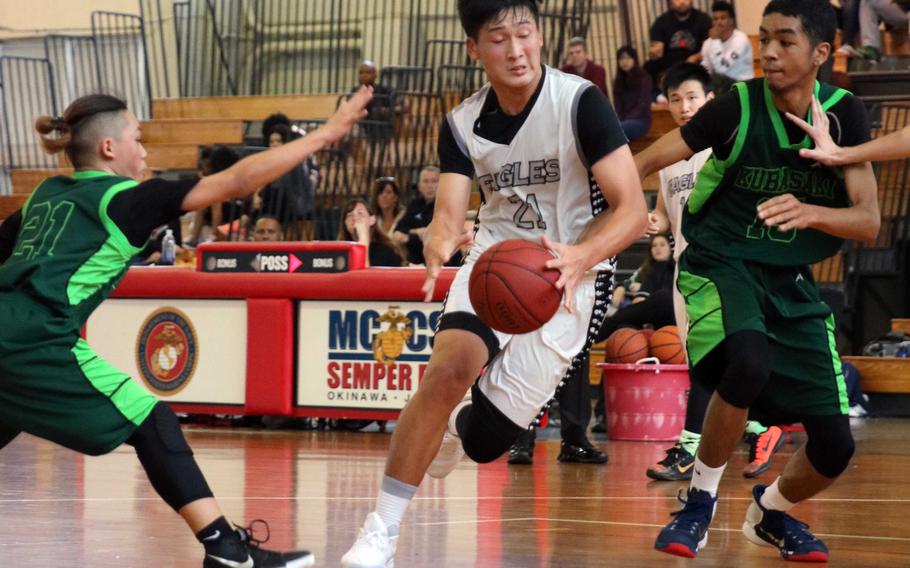 American School of Bangkok's Wei Huang drives between Kubasaki defenders Dylan Canlas and Ilijah Washington during Monday's pool-play game in the Far East Boys Division I basketball tournament. The Eagles beat the two-time defending champion Dragons 54-52.