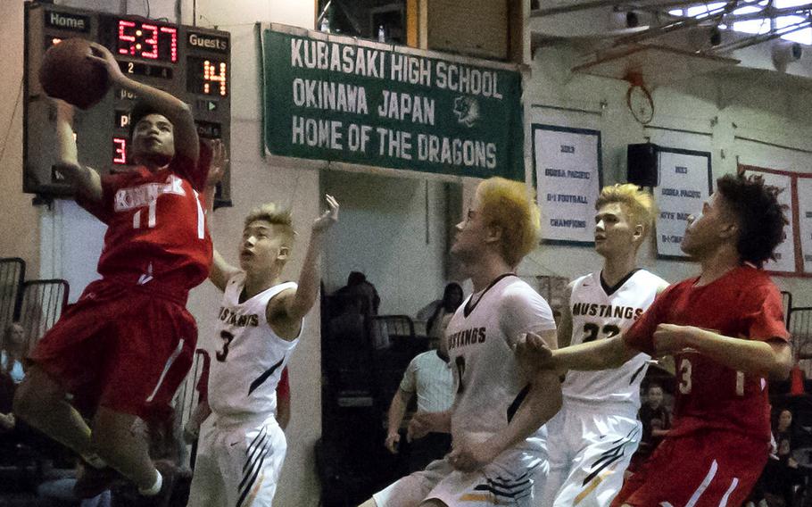 Nile C. Kinnick's Rashad Rapada, left, goes up for a shot against Mark Nishida of American School In Japan during Tuesday's quarterfinal game in the Far East Boys Division I Basketball Tournament. The Mustangs beat the Red Devils 66-38.