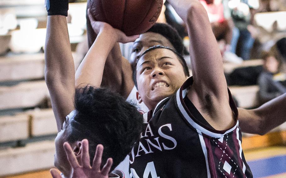 Zama's Hikari Nakamura fights through E.J. King's defenders to shoot during Tuesday's quarterfinal game in the Far East Boys Division II Tournament. The Cobras beat the Trojans 78-51.