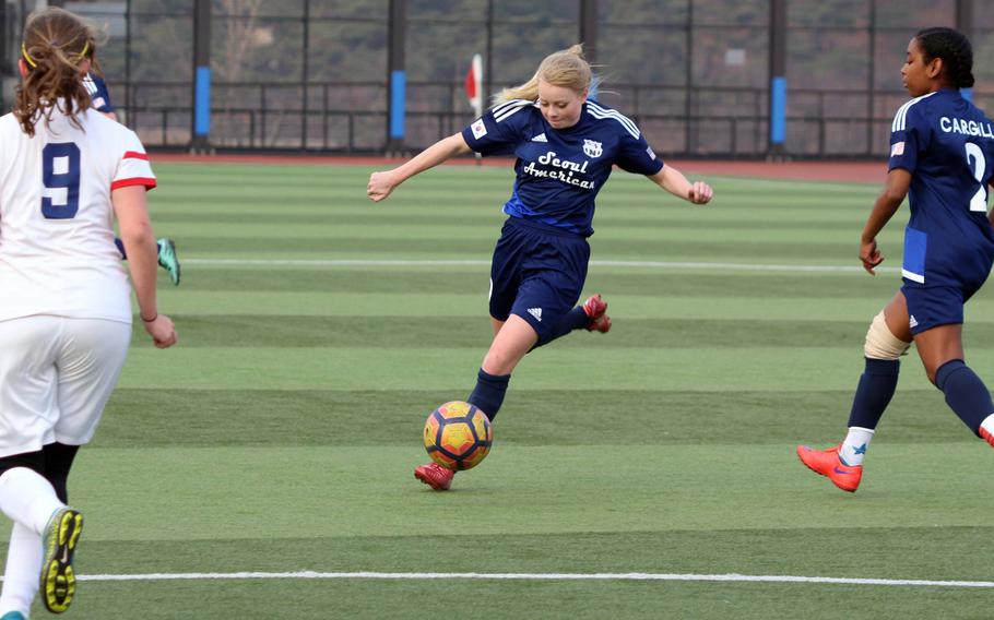 Seoul American's Amy Arnold lets fly between Yongsan's Dora Zoeller and Falcons teammate Natalie Cargill during Wednesday's girls soccer match. The visiting Falcons won 6-2.