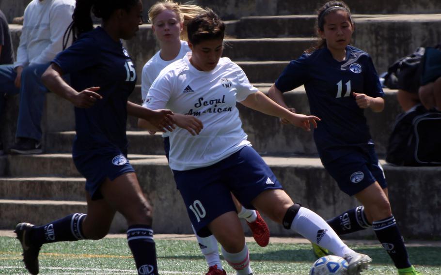 Seoul American's Fran Vido tries to push past Osan's Danielle Dawson and Kelly Kenyon during Saturday's girls soccer match. The Cougars rallied to edge the Falcons 3-2.