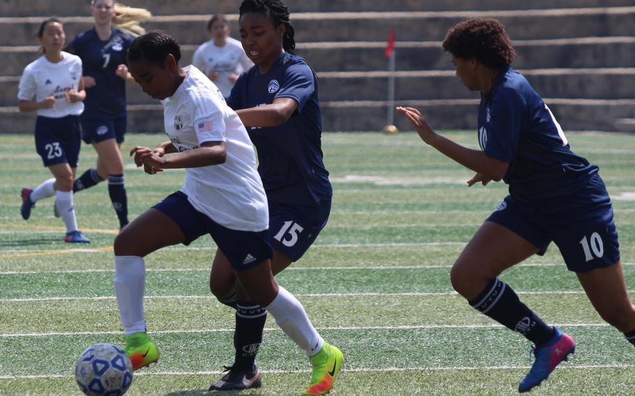 Seoul American's Natalie Cargill tries to dribble away from Osan's Danielle Dawson and Monique Wilson during Saturday's girls soccer match. The Cougars rallied to edge the Falcons 3-2.