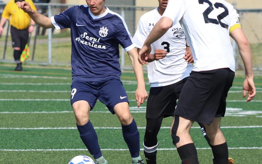 Seoul American's Jeffrey Hindmen dribbles right away from Osan's Lean Copia and Andrew Solak during Saturday's boys soccer match, won by the Falcons 7-1.