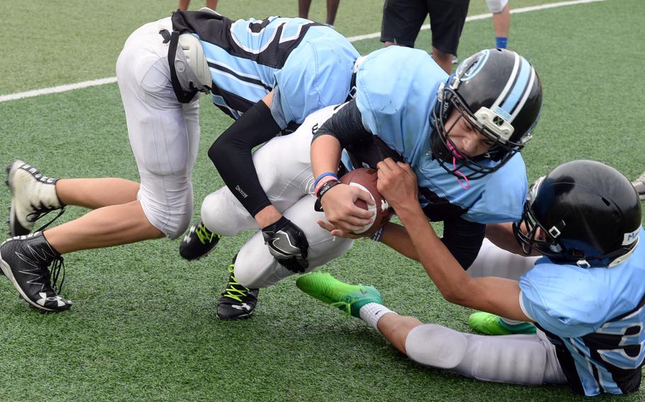 Osan running back Easton Clark tries to bull his way through Cougars defenders Zachary Johnson and Marcus Inthavixay.