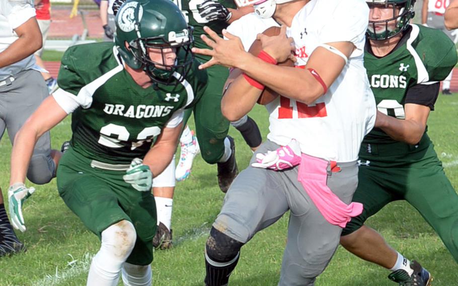 Nile C. Kinnick quarterback Kacey Walker is hounded by Kubasaki defenders Koby Karl and Brandon Puckett. The Red Devils won for the first time in school history on Okinawa, downing the Dragons 24-3.