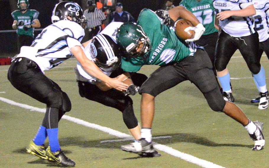 Daegu running back Bishop Fields puts his head down and tries to bull past Osan defenders Coryn Rogers and Kade Woods.