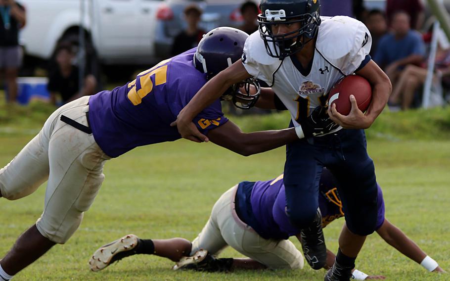 Guam High ballcarrier Jalen Thach tries to elude the tackle of George Washington's Kastino Engichy.
