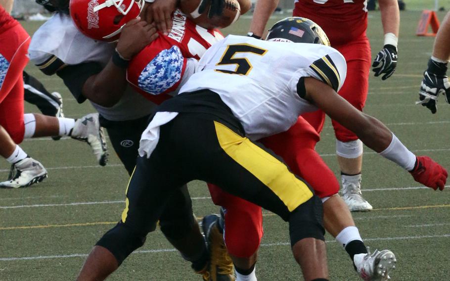 Kadena defenders Uriah Morris and Eric McCarter put the squeeze on Nile C. Kinnick ballcarrier Andrew Urette.