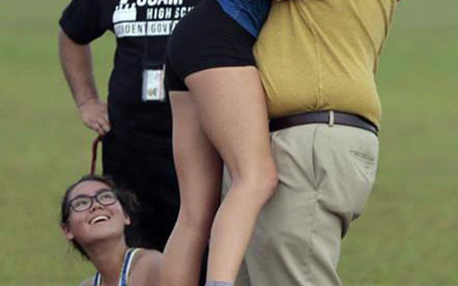 Guam all-island cross country champion Emma Sheedy, a Guam High senior, gets a hug from her father, Guam High principal Jason Sheedy. Standing alongside is athletics director Benjamin Leon Guerrero; seated is teammate Kirsten Riley.
