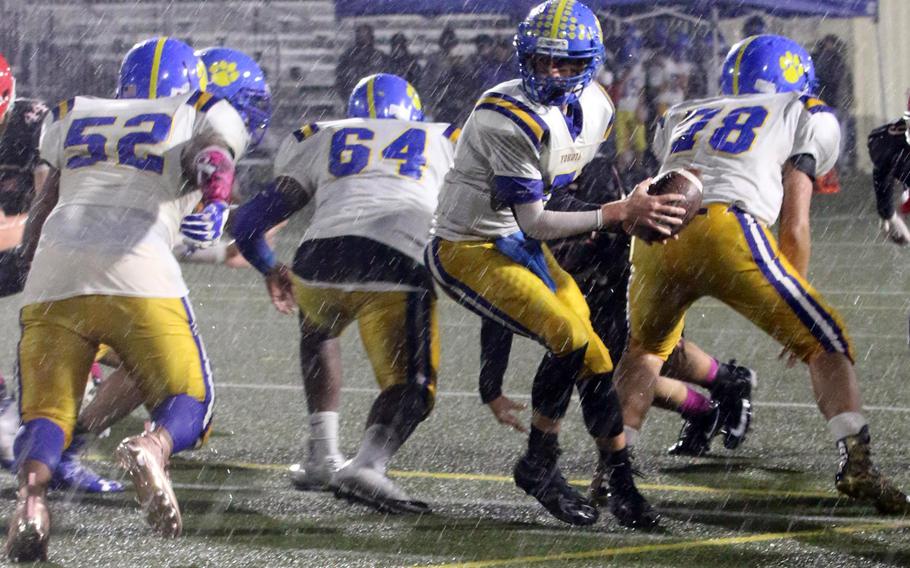 Yokota quarterback Nathan Rundle turns to hand off to Jalen Harrison.
