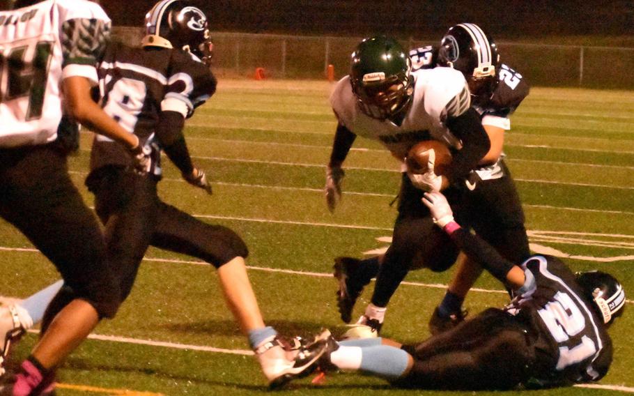 Daegu's Bishop Fields looks to run upfield against Osan defenders Marcus Inthaxivay and Jesse Davis during Friday's football game, won by the Warriors 26-8.