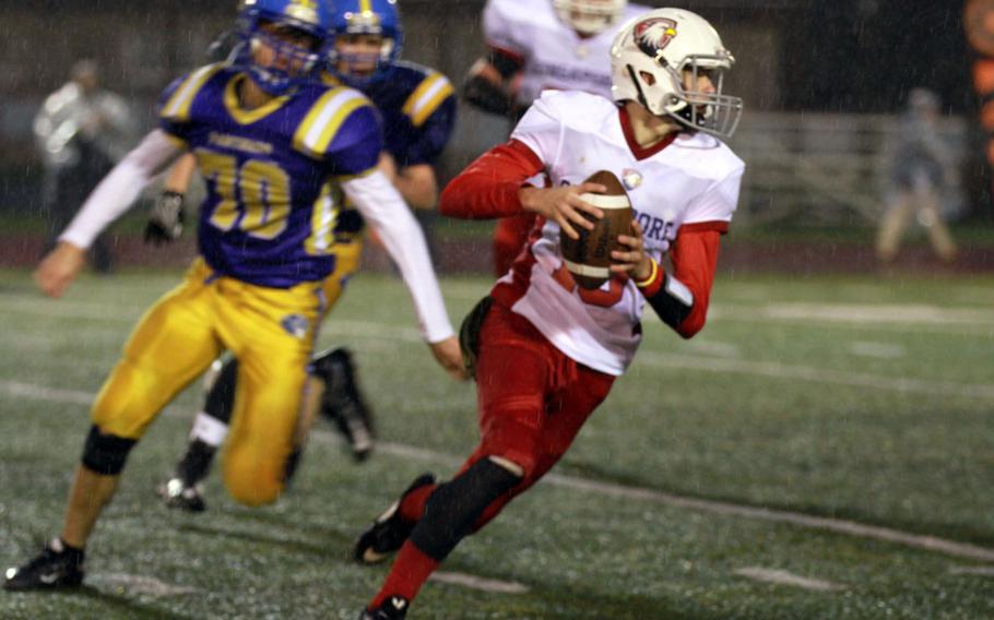 Singapore quarterback Austin Napierski tries to elude the rush of Yokota's Austin Fisher during Monday's football game, won by the Panthers 25-6.