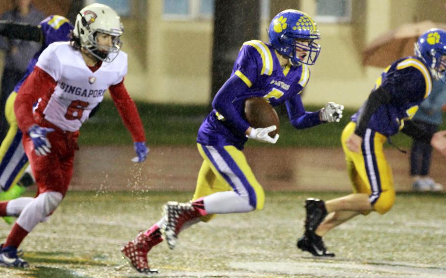 Yokota's Ethan Gaume takes off with an interception ahead of Singapore's Tyler Wahl during Monday's football game, won by the Panthers 25-6.