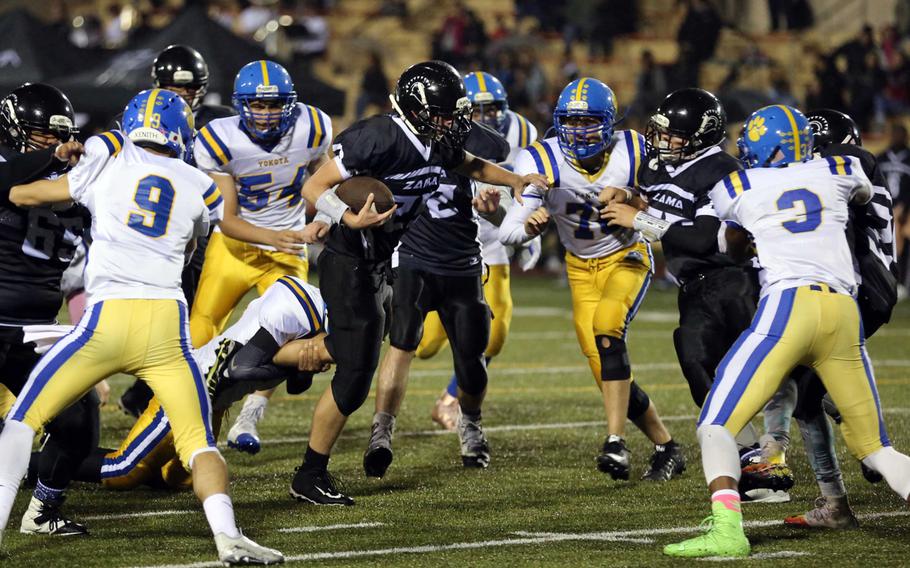 Zama running back Jacob Clark tries to wriggle free of a Yokota tackler.