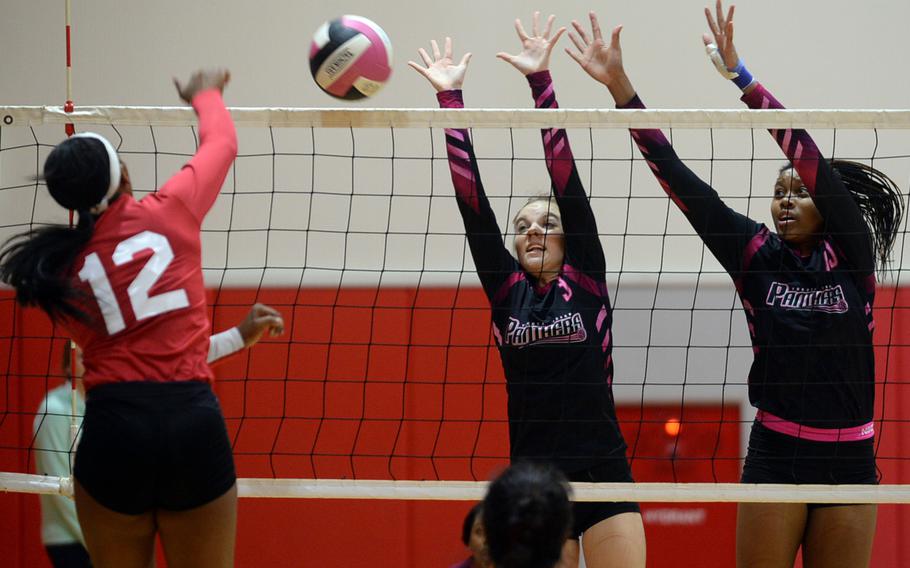 Nile C. Kinnick's Jade McGinnis tries to blast one past the block of Yokota's Ashley Woodruff and Britney Bailey.