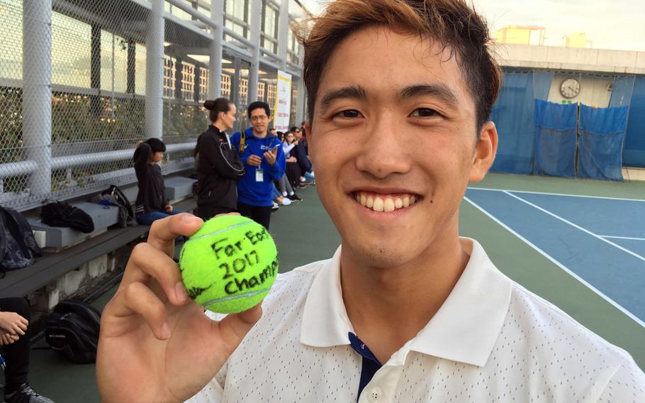 American School In Japan senior Noah Inahara holds up a ball he signed commemorating his second straight Far East tennis boys singles title.