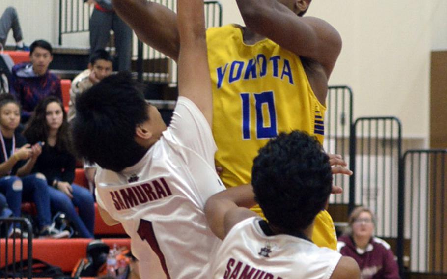Yokota's Kishaun Kimble-Brooks plows into Matthew C. Perry defenders Jericho Eusebio and Daniel Riley during Friday's Japan boys basketball game, won by the Panthers 68-48.