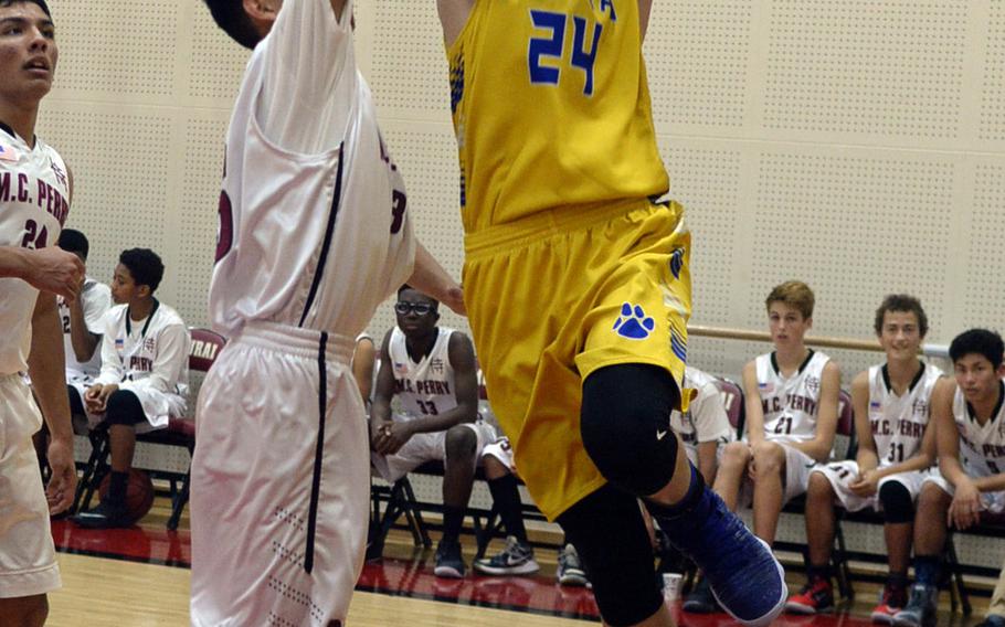 Yokota's Renyck Robertson drives to the basket on Matthew C. Perry's Ty Brown during Friday's Japan boys basketball game, won by the Panthers 68-48.