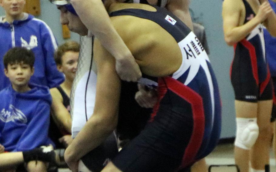 Roberto Salas of Seoul American prepares to lift Peter Teachout of Humphreys during Saturday's three-way dual-meet event at Seoul American. Salas beat Teachout in the 135-pound bout by technical fall.