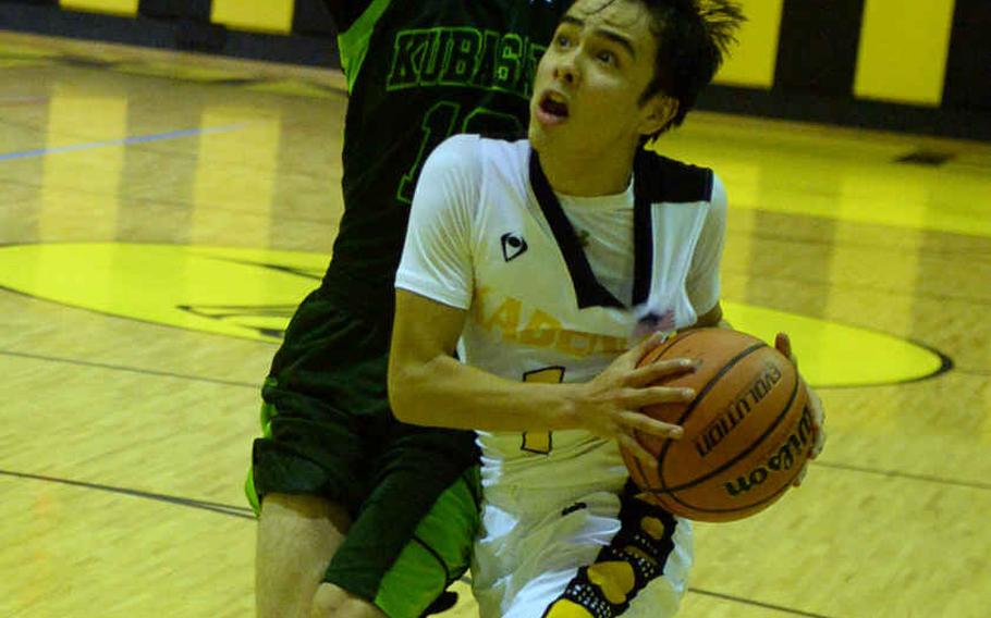 Kadena's Cody Chambers drives to the basket against Kubasaki's Jonathan Hoppe during Friday's boys basketball game. Chambers hit a three-point goal just inside the midcourt line as time ran out to rally the Panthers past the Dragons 40-39.