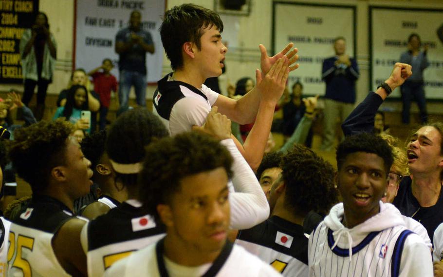 Kadena senior guard Cody Chambers rides on the shoulders of teammates and spectators and applauds after his three-point shot from just inside midcourt rallied the Panthers past Kubasaki 40-39 in Friday's boys basketball game.