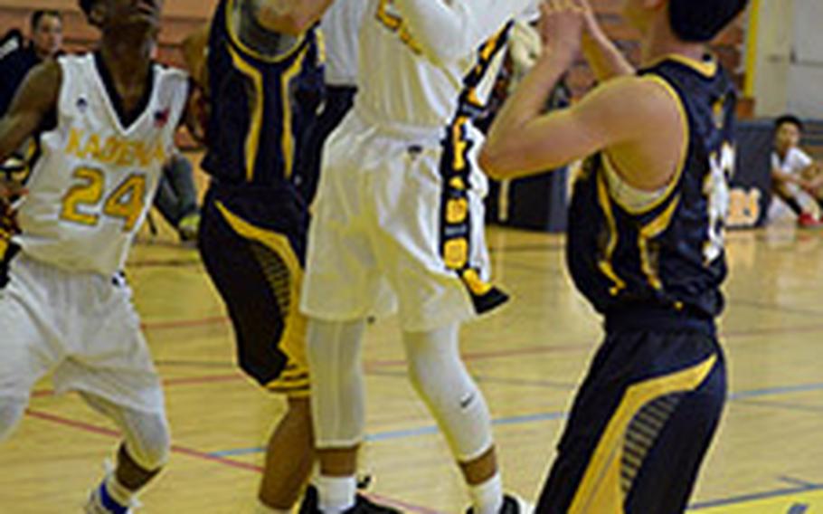 Kadena's Eugene Robinson goes up for a rebound between two Kitanakagusuku players during Saturday's boys basketball game, won by the Panthers 77-62.