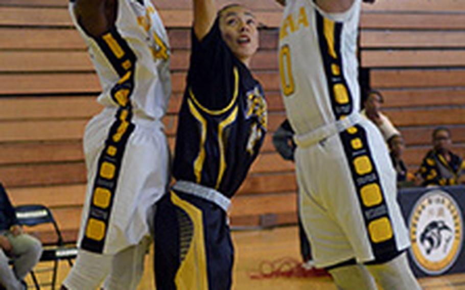 Kadena's Montez Young Jr. and Eric McCarter tower over Kitanakagusuku's Takuto Hirakawa skying for a rebound during Saturday's boys basketball game, won by the Panthers 77-62.