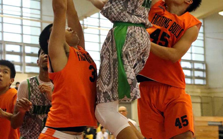 Kubasaki's Elonzo Higginson III skies for a shot between two Maehara defenders during Sunday's boys championship game in the 12th Okinawa-American Friendship Basketball Tournament. The Dragons downed the Fighting Bulls 68-54 to win their fourth title in six finals appearances since the tournament's inception in 2007.