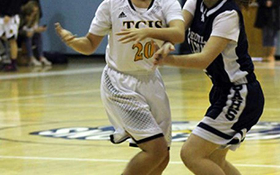 Seoul American's Kylie Hart passes past Taejon Christian's Kunlan Yang during Saturday's Korea girls basketball game, won by the Falcons 70-35.