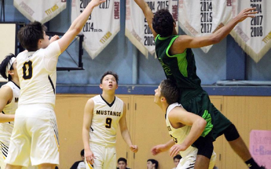 Kubasaki's Ilijah Washington collides with American School In Japan's Oliver Rogers under the basket as ASIJ teammates Jack Latimore and Tyler Evert eye the action during Saturday's boys final in the 2nd ASIJ Kanto Classic. The host Mustangs downed the Dragons 55-33.