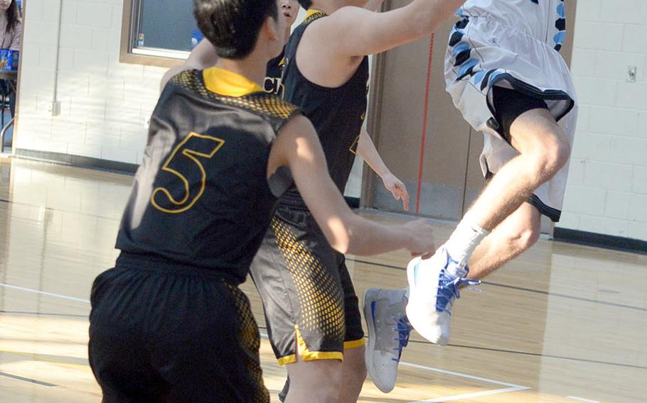 Osan's Joseph Betts shoots over two Taejon Christian defenders during Thursday's Korea Blue Division boys tournament quarterfinal, won by the Cougars 83-37, the most one-sided margin of the 10 games played Thursday.